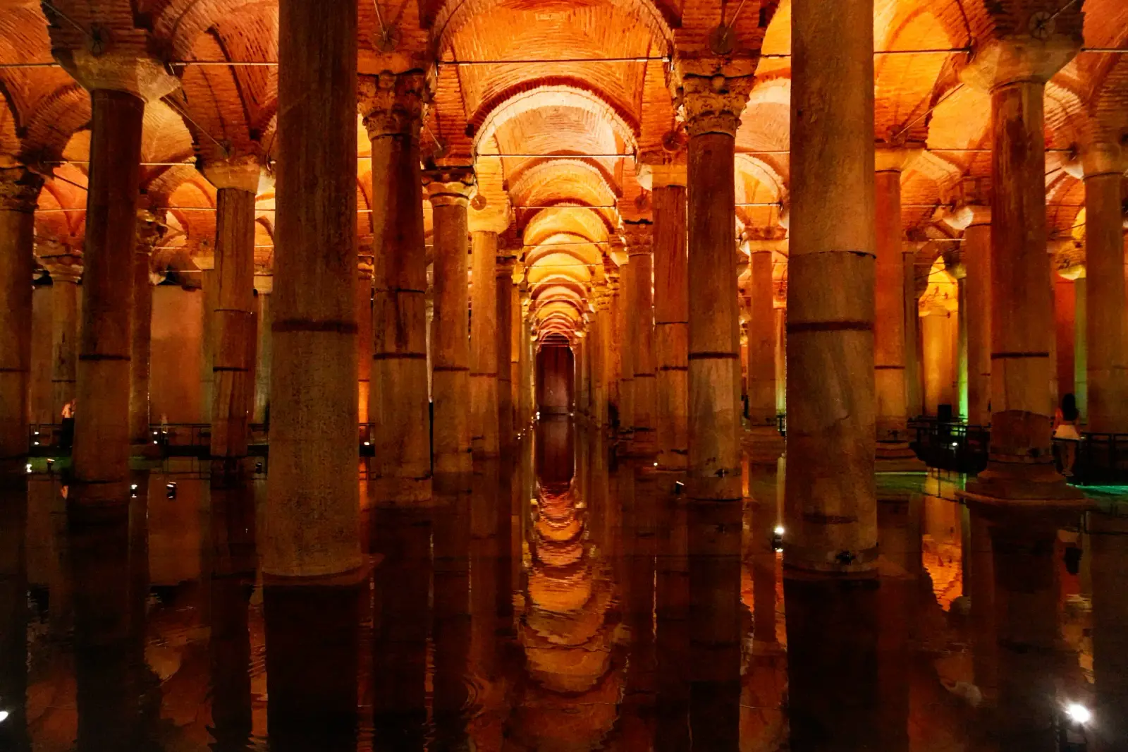 The cistern along its long axis: rows of columns under warm brick vaults, doubled in the still water below.
