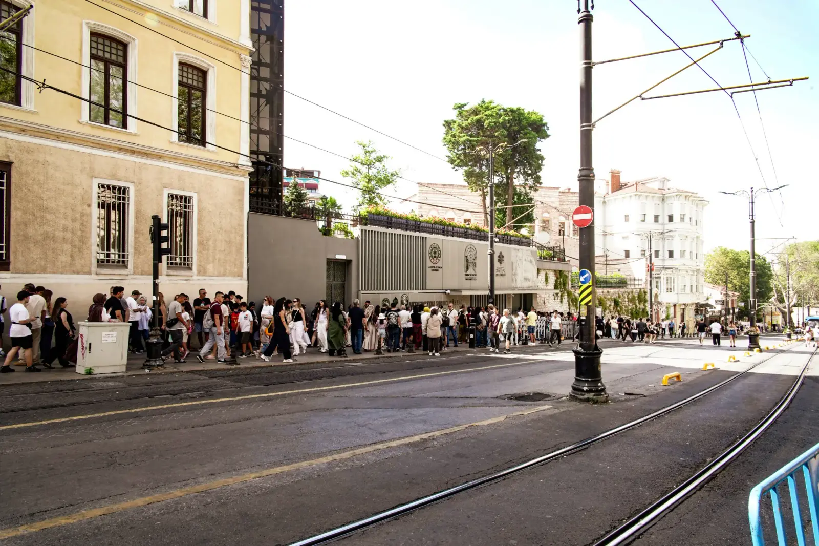 The museum entrance seen from across the tram line, a long queue along the pavement in front of it.