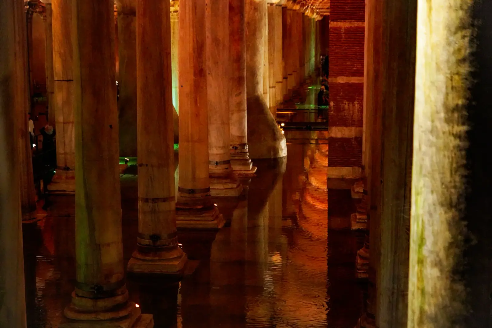 Column shafts standing in dark water at the far end of the chamber, amber light rippling across the surface.
