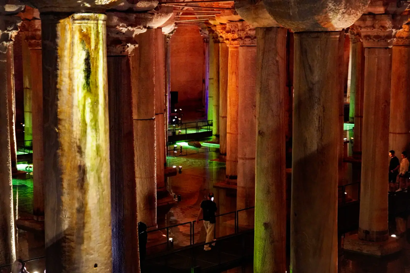 The chamber under its coloured lighting: green and violet washing the water between amber-lit columns.