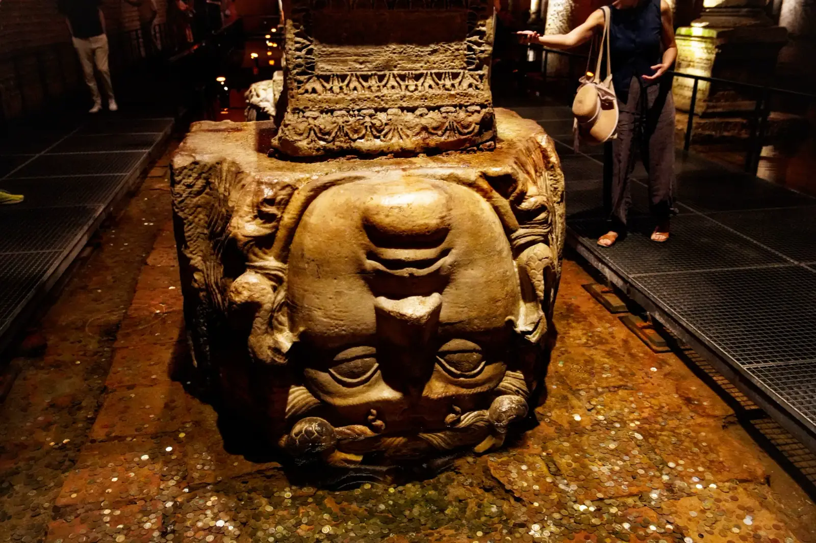 The upside-down Medusa head serving as a column base, worn and damp under focused light.